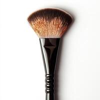 A makeup brush with a fan shape, designed for applying and blending cosmetics. photo