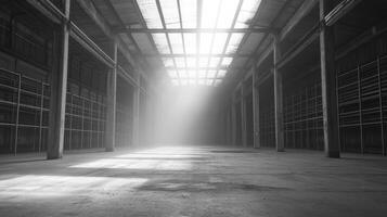 A spacious, empty industrial warehouse illuminated by beams of light through the roof photo