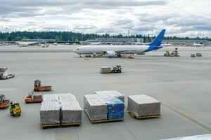 A busy airport scene with cargo pallets and a parked aircraft. photo