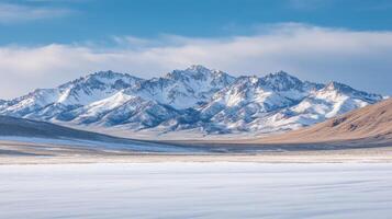 A serene winter landscape featuring snow-capped mountains under a clear blue sky photo