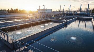 A wastewater treatment facility with aeration tanks and industrial structures under a sunset photo