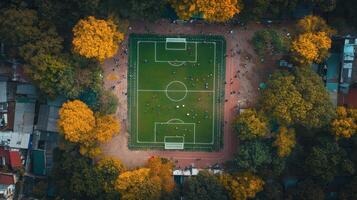 Aerial view of a vibrant soccer field surrounded by autumn trees and people playing. photo