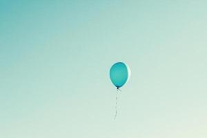 A solitary blue balloon floats against a clear sky, evoking feelings of freedom and nostalgia. photo