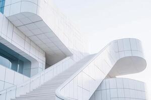 A modern architectural structure featuring sleek white stairs and curves against a light background. photo