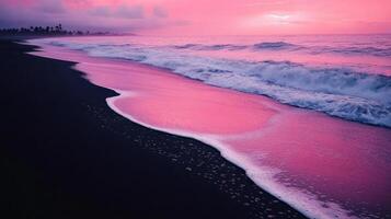 A serene beach at sunset with pink hues reflecting on the waves and dark sand. photo