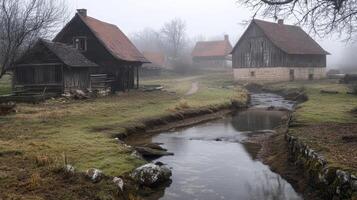 A serene foggy landscape featuring rustic houses beside a gentle stream. photo