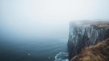 A foggy cliffside overlooking calm waters, evoking a sense of solitude and nature's beauty. photo