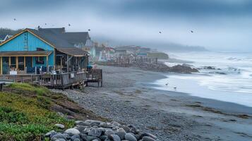 A coastal scene with fog, featuring buildings, rocky shore, and gentle waves. photo