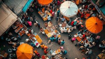 A bustling market scene with vendors and shoppers under orange umbrellas. photo