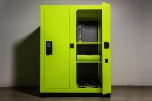 A bright green locker with shelves, containing a towel, shoes, and a water bottle. photo