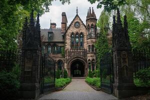 A grand, gothic-style mansion surrounded by lush greenery and ornate gates photo