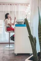 Young non-binary person applying makeup in front of a mirror in a bright room photo