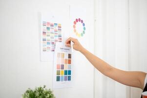 Close up of a hand sticking or taking off a printed color palette on the wall, Designer in office. photo