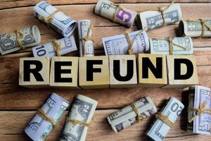 Concept word Refund on wooden blocks on a wooden table with dollar bills photo