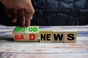 Concept word Good or bad news, hand flips cubes and changes the words bad news to good news on wooden blocks on a wooden table photo