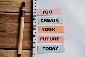 Concept of You Create Your Future Today write on sticky notes isolated on Wooden Table. photo