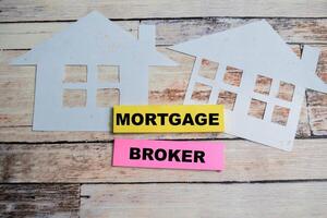 Concept of Mortgage Broker write on sticky notes isolated on Wooden Table. photo