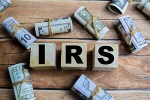 Concept word IRS - Internal Revenue Services on a wooden table with dollar bills photo