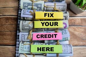 Concept of Fix Your Credit Here write on sticky notes isolated on Wooden Table. photo