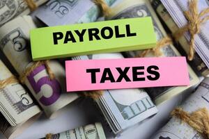 Concept Payroll Taxes on sticky notes on a wooden table with dollar bills photo