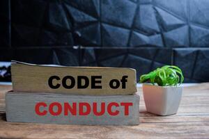 Books with words Code of Conduct on wooden table and black background photo