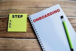 Concept of Onboarding write on book and Step on sticky notes isolated on Wooden Table. photo