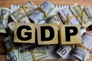 Concept word GDP on wooden blocks on a wooden table with dollar bills photo