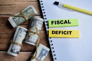 Concept Fiscal Deficit on sticky notes on a wooden table with dollar bills photo
