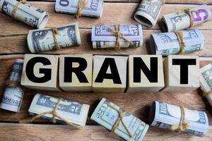 Concept word Grant on wooden blocks on a wooden table with dollar bills photo