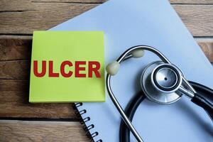 Concept of Ulcer write on sticky notes isolated on Wooden Table. photo
