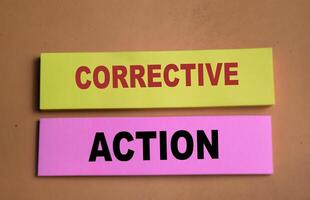 Concept of Corrective Action write on sticky notes isolated on Wooden Table. photo