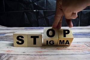 Concept word Stop stigma symbol, doctor turns with words stop stigma on wooden blocks on a wooden table photo