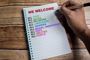 Concept of We Welcome write on book with keywords isolated on Wooden Table. photo