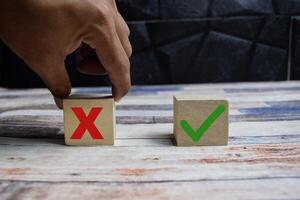 Concept word Yes or No choice symbol. hand making between two cubes with yes and no icon on wooden blocks on a wooden table photo