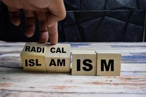 Concept word Radicalism or Islamism, turns cube and changes the word radicalism to islamism on wooden blocks on a wooden table photo