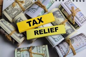 Concept Tax Relief on sticky notes on a wooden table with dollar bills photo