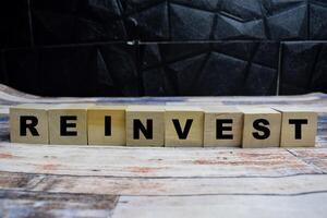 Concept word Reinvest on wooden blocks on a wooden table photo