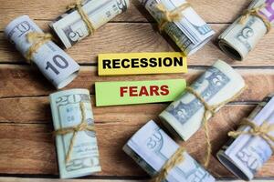 Concept Recession Fears on sticky notes on a wooden table with dollar bills photo
