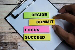 Concept of Decide Commit Focus Succeed write on sticky notes isolated on Wooden Table. photo