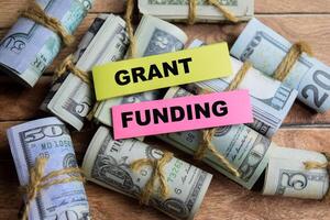 Concept Grant Funding on sticky notes on a wooden table with dollar bills photo