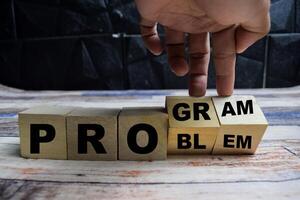 Concept word Solving a problem and making program and changes the word problem to program on wooden blocks on a wooden table photo