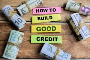 Concept word How to build good credit on wooden blocks on a wooden table with dollar bills photo