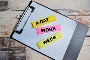 Concept of 4 Day Work Week write on sticky notes isolated on Wooden Table. photo