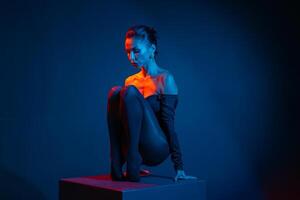 Stylized portrait of a woman posing in dramatic light, seated with expressive emotion. photo