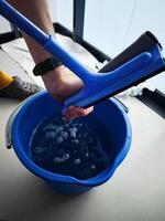 Window cleaner squeezing water from squeegee into bucket photo