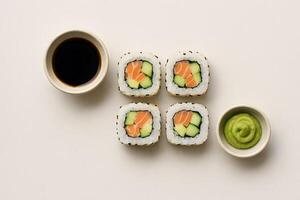 Top view of salmon sushi rolls with cucumber and avocado served with soy sauce and wasabi on light background, traditional Japanese cuisine photo