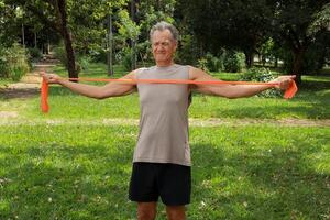 Mature Man at the Park using a fitness Rubber band or Stretch Bands for increase mobility and Strength photo