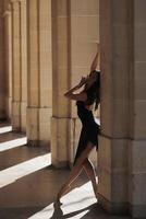 Ballet dancer striking elegant pose in stone arcade. Soft directional lighting photo