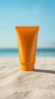 Orange tube of sunscreen sits atop soft sand at beach, with calm turquoise water lapping at shore and sunlight creating a warm ambiance on the scene photo