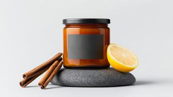 Amber jar sits elegantly with a black label, accompanied by cinnamon sticks and a fresh lemon slice, arranged on a smooth stone surface photo